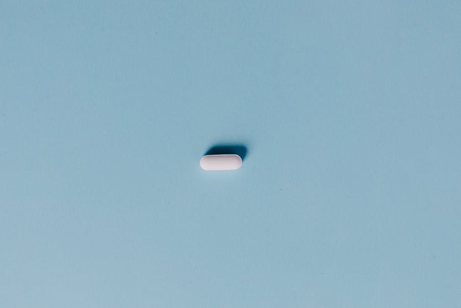 Single white pill on a blue background, representing medicine or healthcare.
