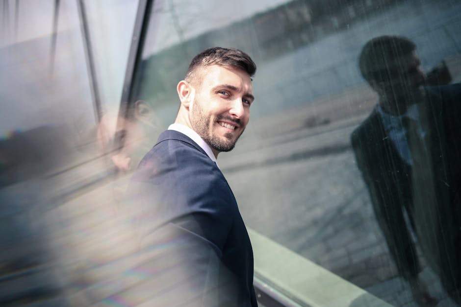 Businessman smiling confidently by a glass wall reflecting cityscape. Professional and optimistic vibe.