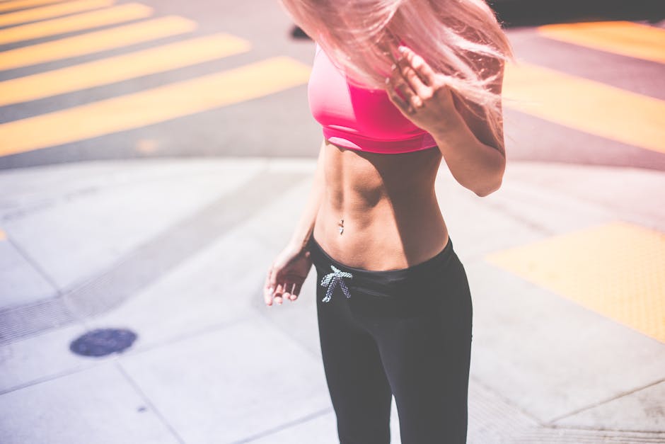 Athletic woman in pink activewear showing toned abs in urban San Francisco setting.
