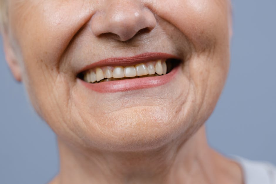 A detailed close-up of a senior woman's smile showcasing her natural teeth and wrinkles.