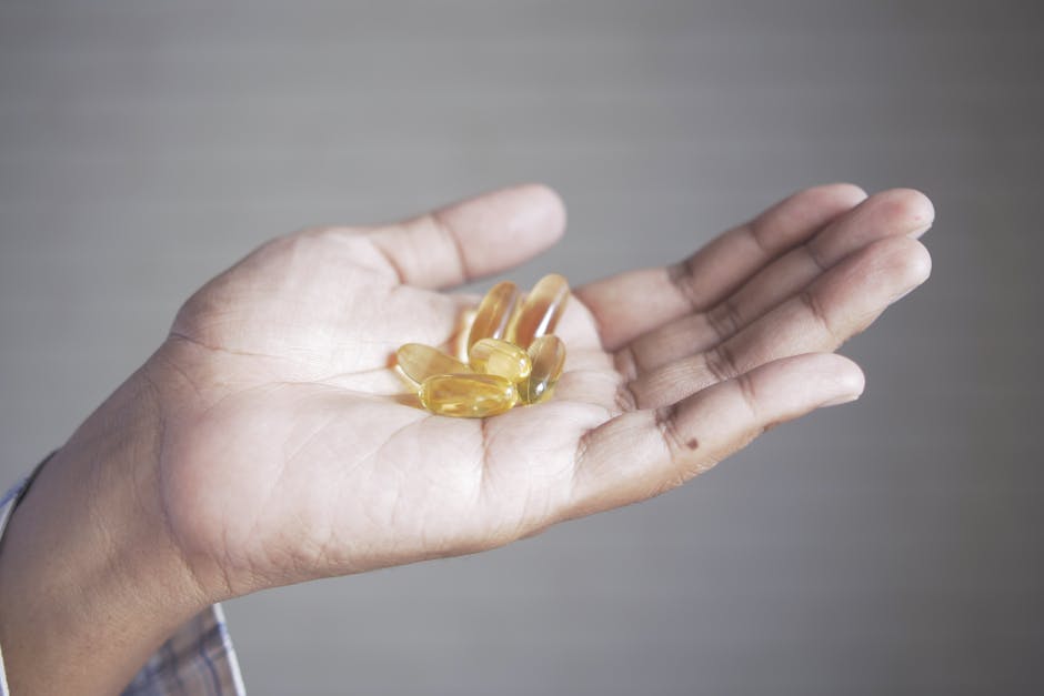 Hand holding yellow capsules, representing supplements and health care.