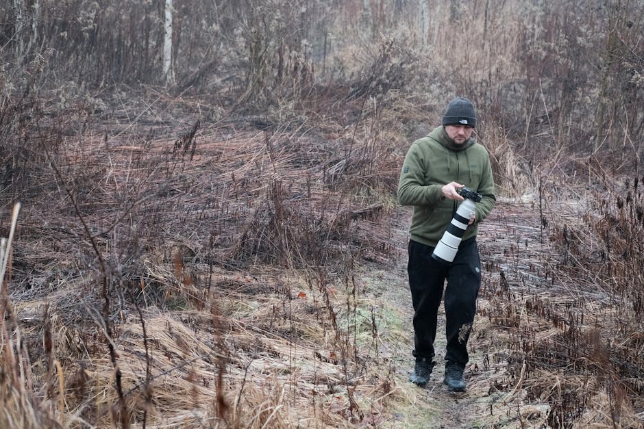 A photographer explores a barren winter landscape, capturing nature with a long telephoto lens.