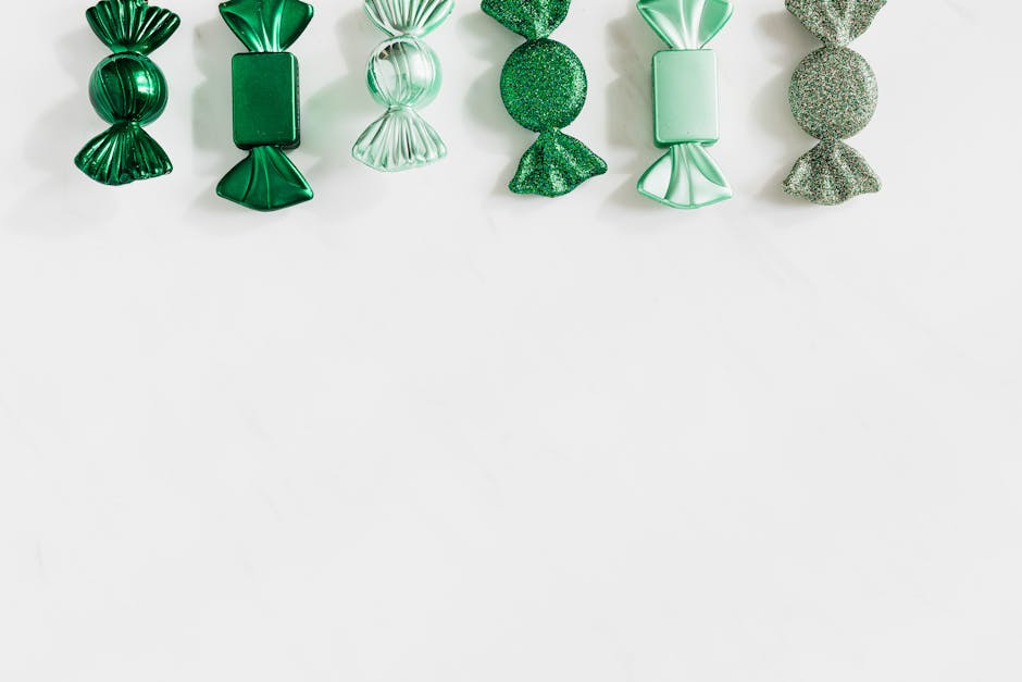 A collection of green wrapped candies arranged in a row on a white background.