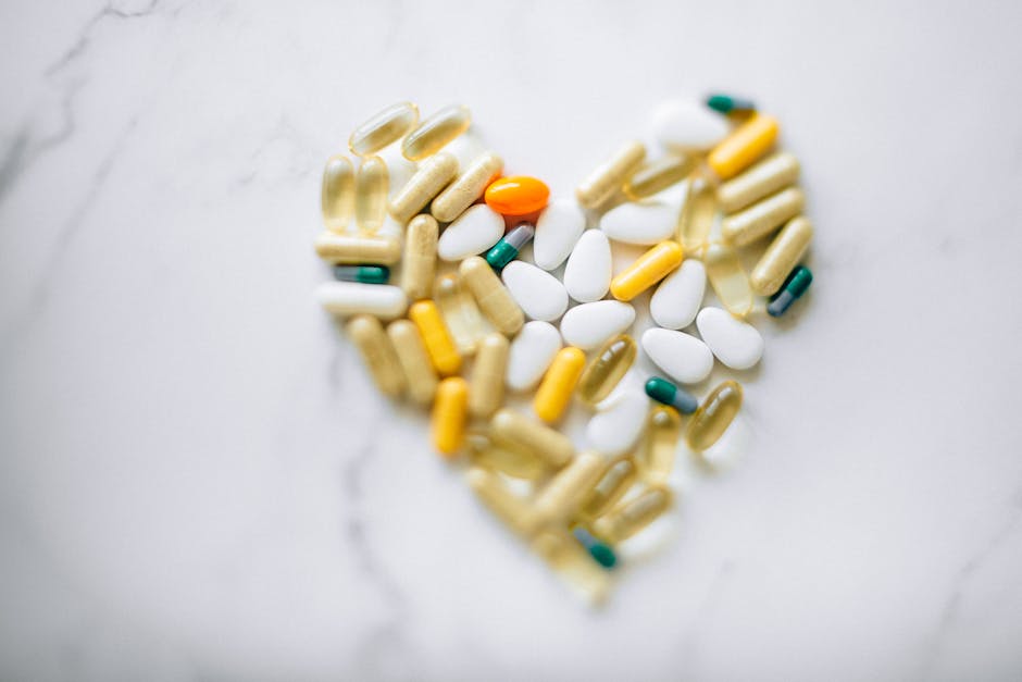 Colorful pills arranged in heart shape on a marble surface, symbolizing health and wellness.