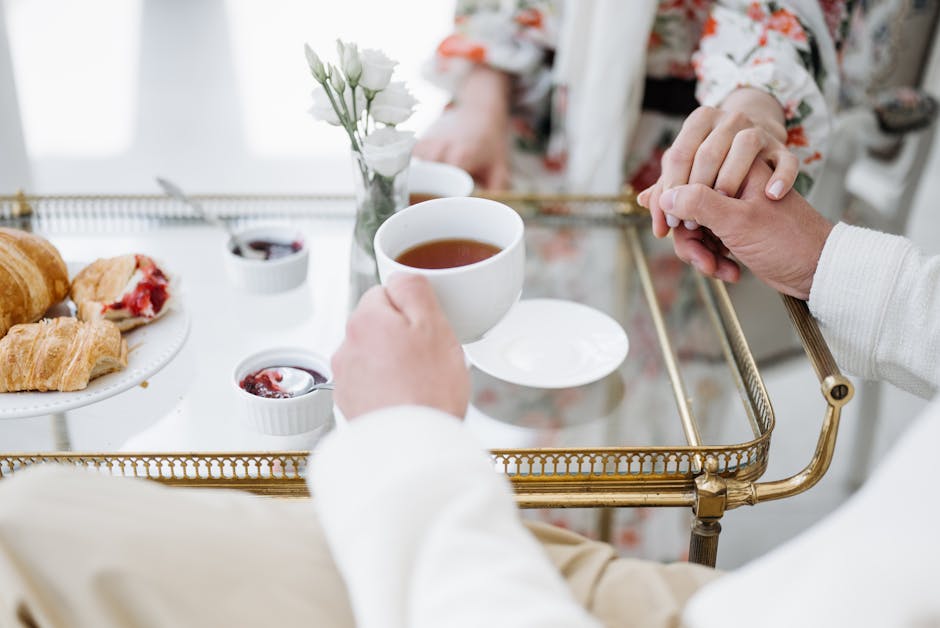 A cozy breakfast setting with tea, pastries, and a couple holding hands, creating a warm mood.