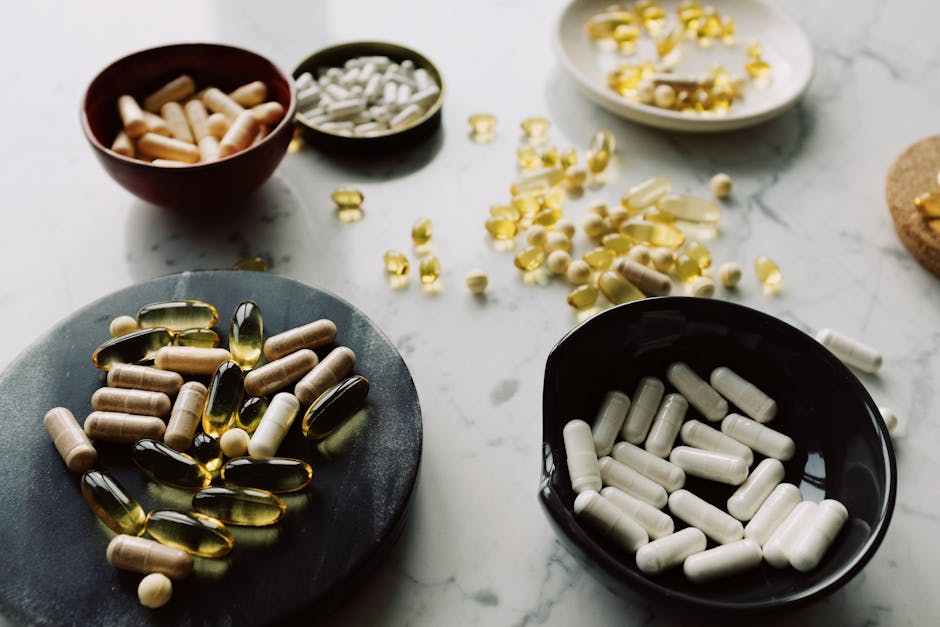 A variety of capsules and tablets displayed in bowls on a marble surface, emphasizing health and wellness.