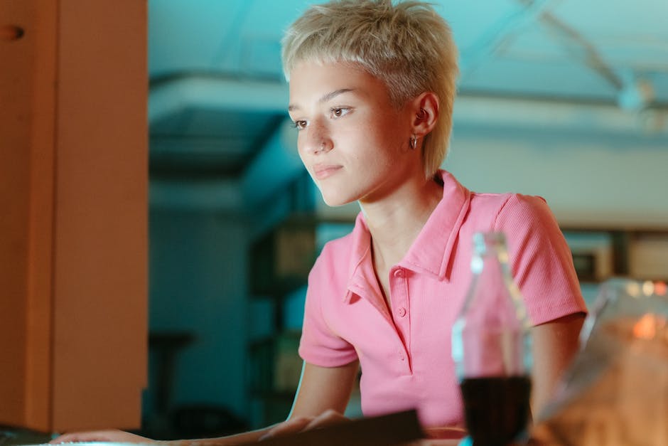 A focused woman with short hair works on her laptop in a cozy indoor setting.