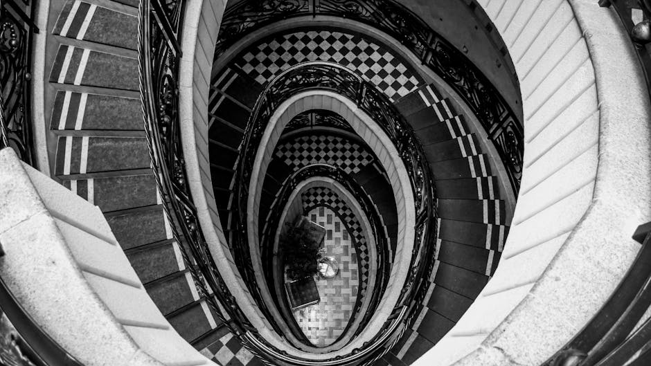 Elegant spiral staircase captured from above in monochrome, highlighting geometric patterns.