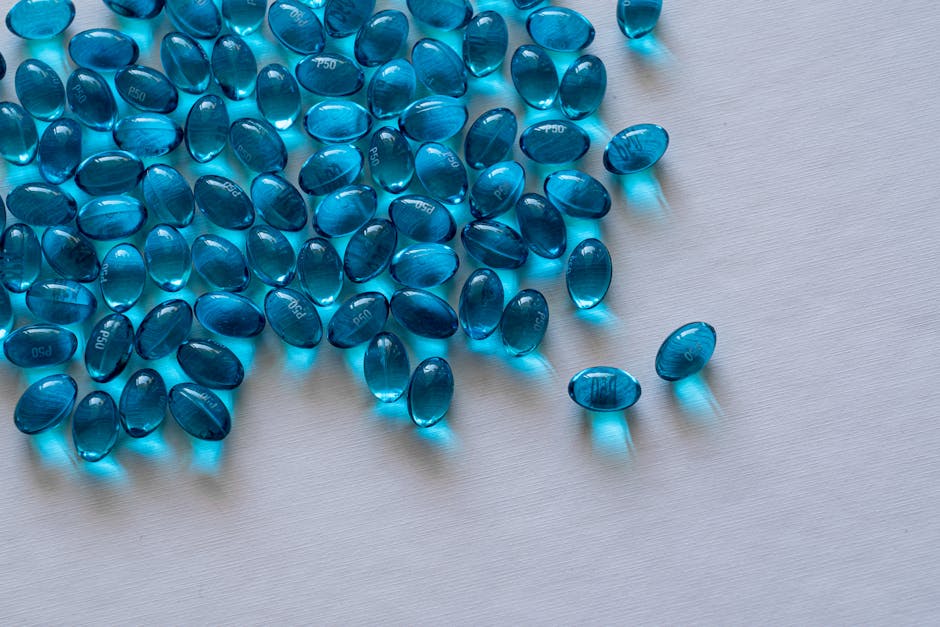 A close-up view of scattered blue gel capsules on a white surface, showcasing their glossy texture.