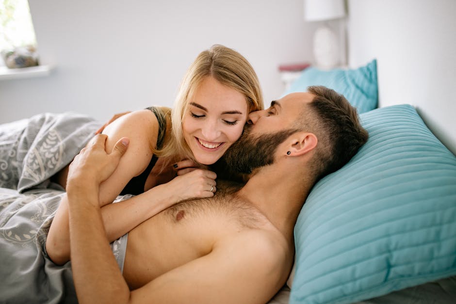 Smiling couple embracing in bed, expressing love and togetherness in a cozy bedroom.