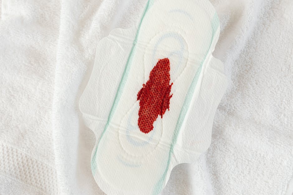 Detailed view of a sanitary pad with a blood stain, highlighting menstruation theme.