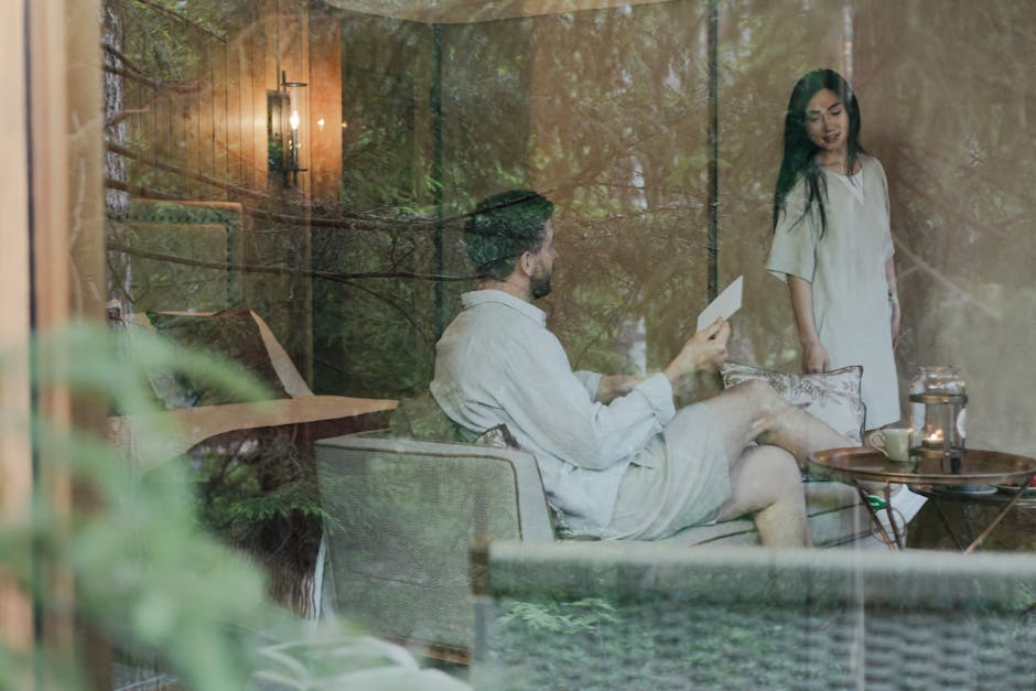 A couple enjoys a peaceful conversation in a cozy living room with a glass wall.
