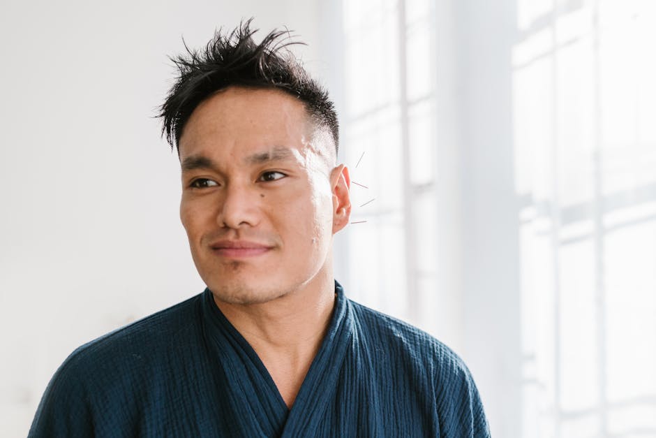 A contemplative man in a blue robe smiles softly in natural light.